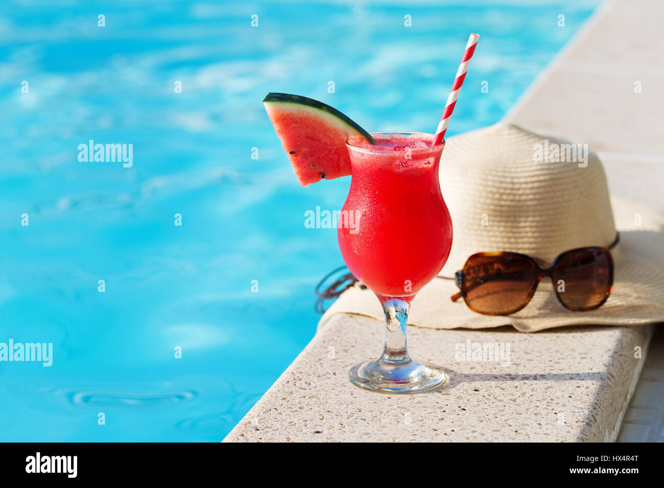 Vetro fresco di acqua-Frullato al melone drink con gli occhiali da sole e cappello di paglia e pantofole sul bordo di una piscina - vacanza concetto tropicale Foto Stock