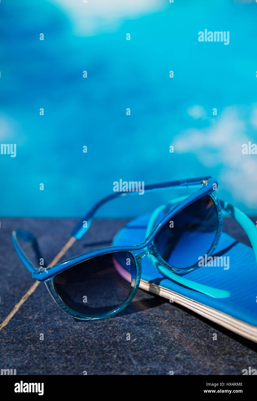 Pantofole blu e occhiali da sole vicino alla piscina - vacanza concept Foto Stock