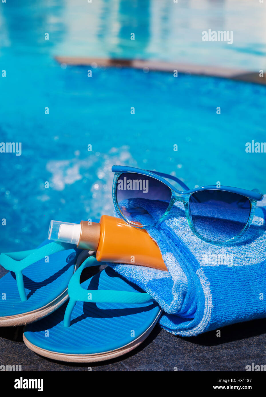 Blue pantofole, sunsscreen crema e occhiali da sole vicino alla piscina - vacanza concept Foto Stock