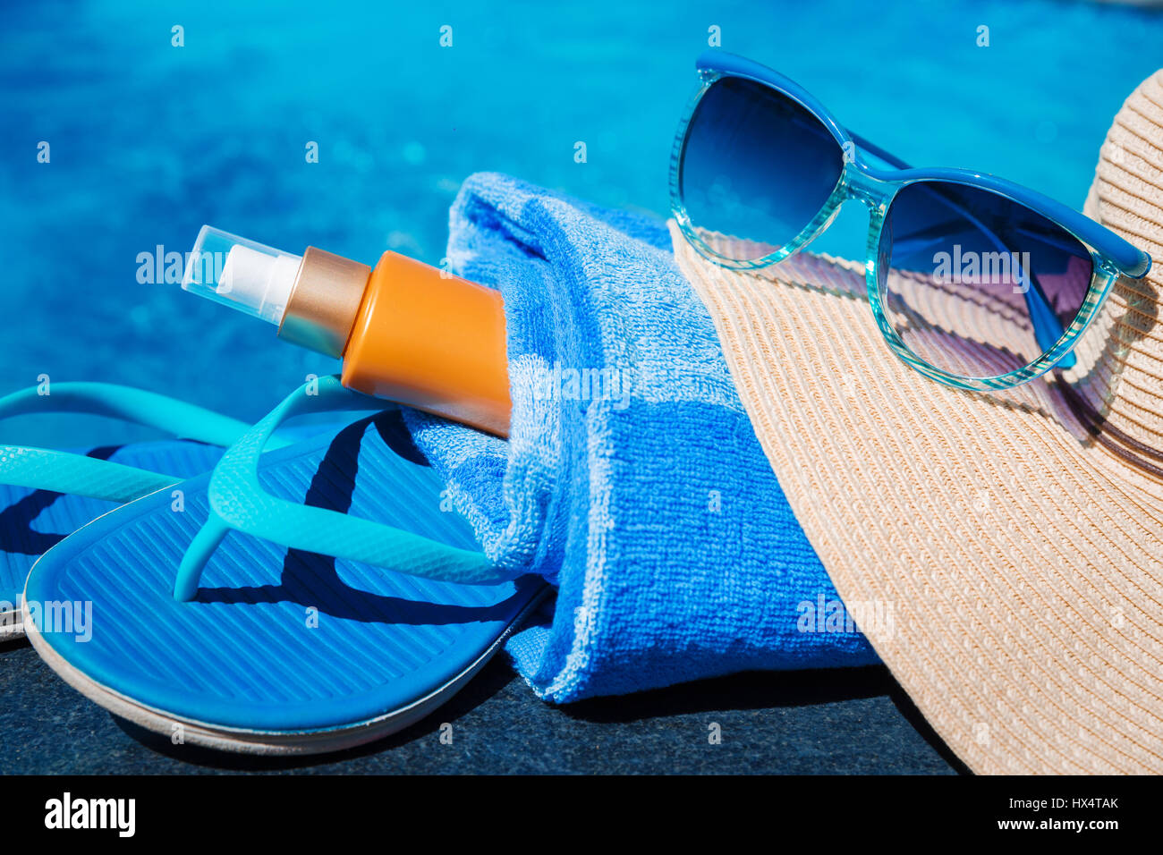 Blue pantofole, sunsscreen crema, il cappello di paglia e occhiali da sole vicino alla piscina - vacanza concept Foto Stock