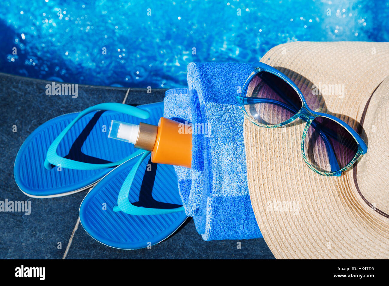 Blue pantofole, sunsscreen crema, il cappello di paglia e occhiali da sole vicino alla piscina - vacanza concept Foto Stock
