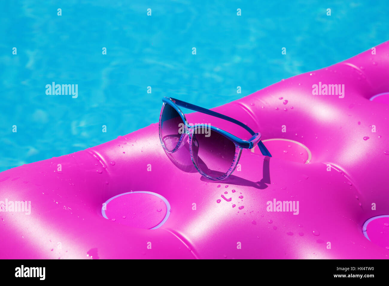 Occhiali da sole con materasso rosa presso la piscina - vacanza concetto tropicale Foto Stock