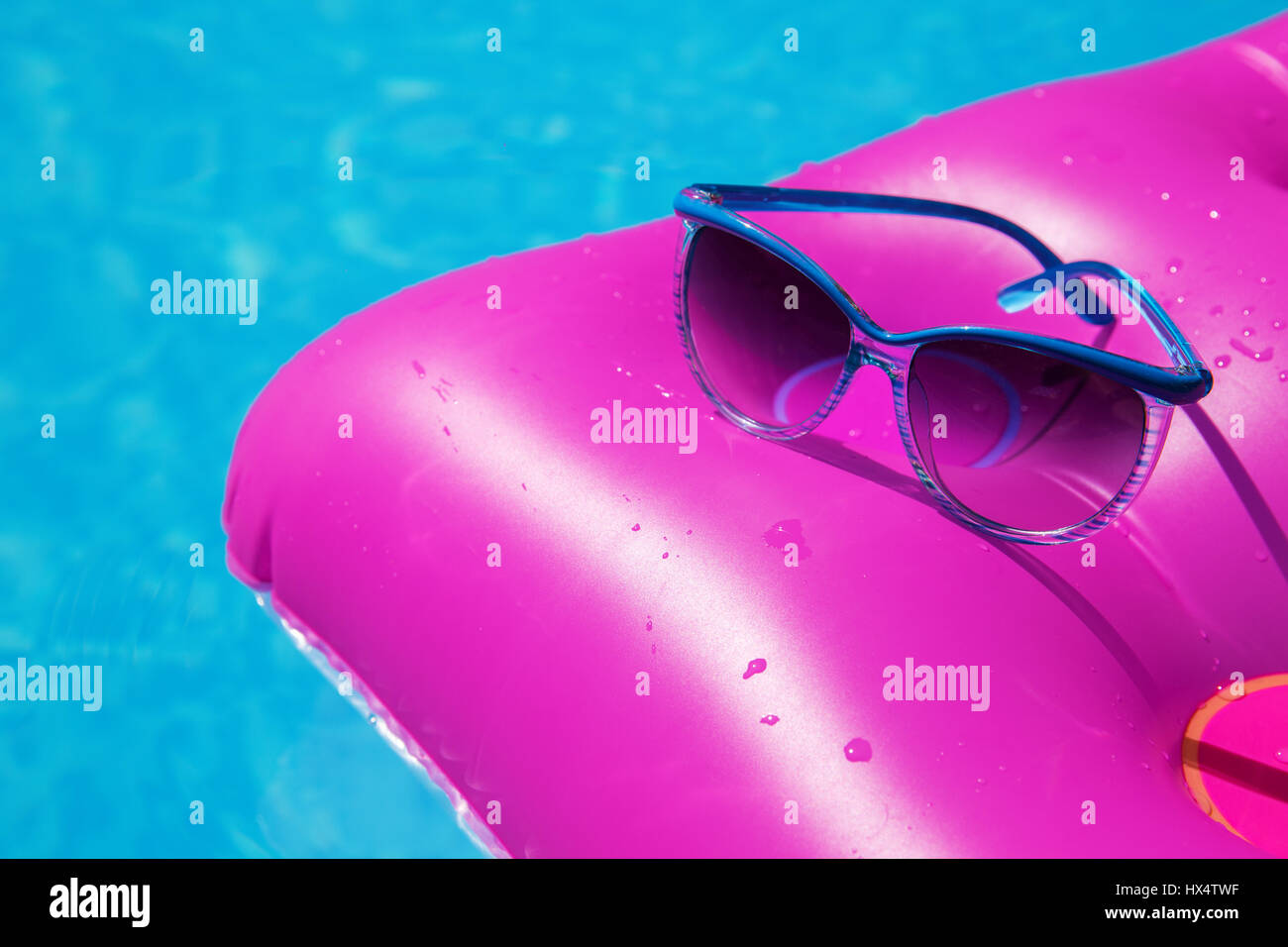 Occhiali da sole con materasso rosa presso la piscina - vacanza concetto tropicale Foto Stock