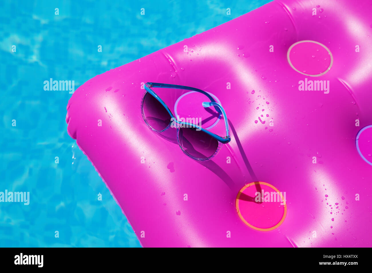 Occhiali da sole con materasso rosa presso la piscina - vacanza concetto tropicale Foto Stock