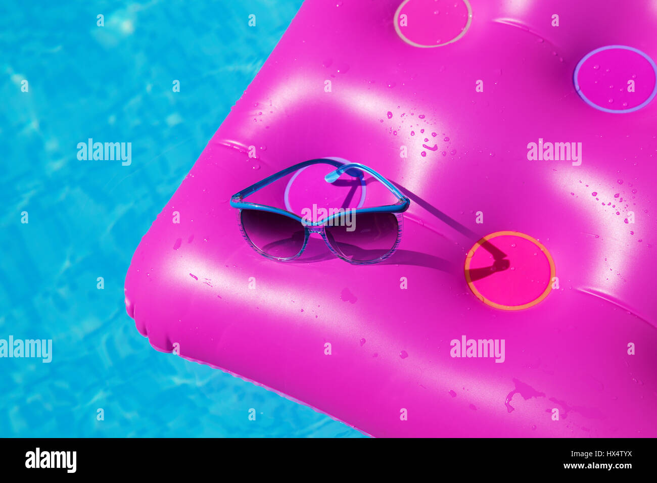 Occhiali da sole con materasso rosa presso la piscina - vacanza concetto tropicale Foto Stock