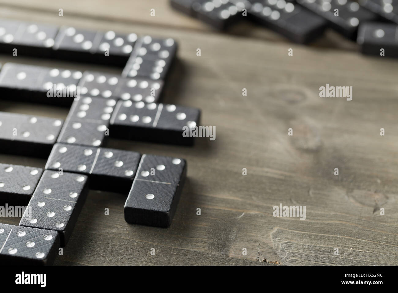 Gioco di Domino con Domino pietre su sfondo di legno; messa a fuoco selettiva su domino pietra davanti Foto Stock