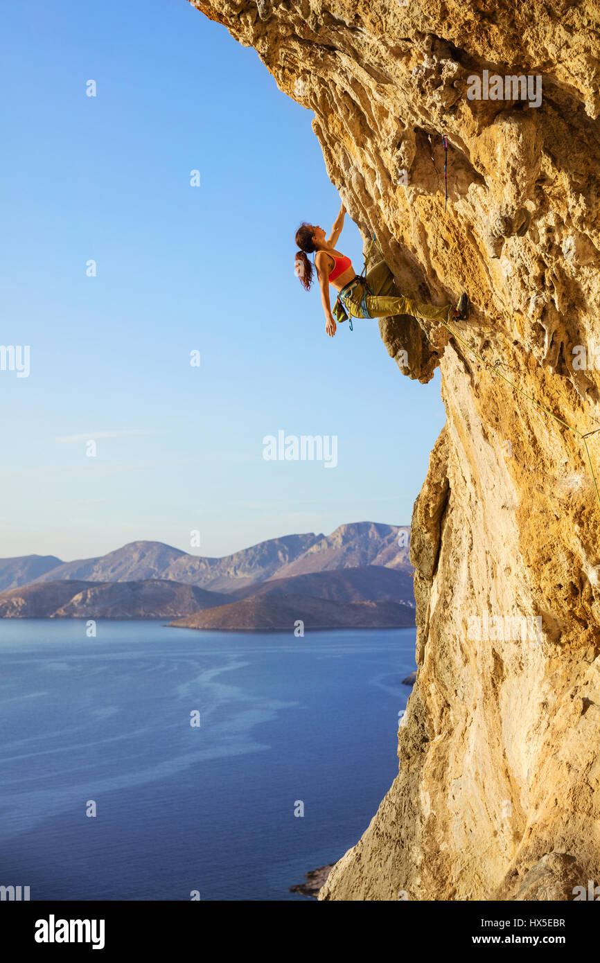 Femmina di rocciatore sul percorso impegnativo, guardando il cliff, vista della costa sottostante Foto Stock