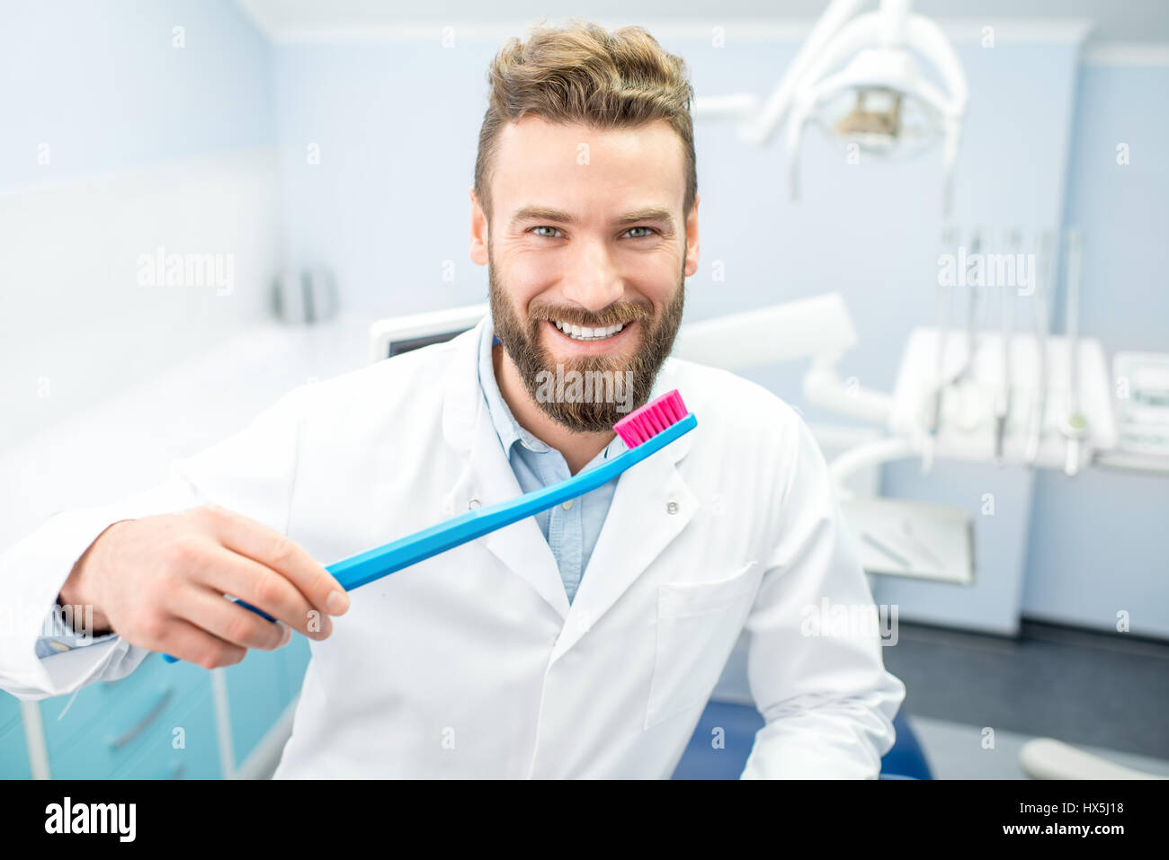 Ritratto di dentista divertenti in uniforme con spazzolino da denti di  grandi dimensioni presso lo studio dentistico Foto stock - Alamy