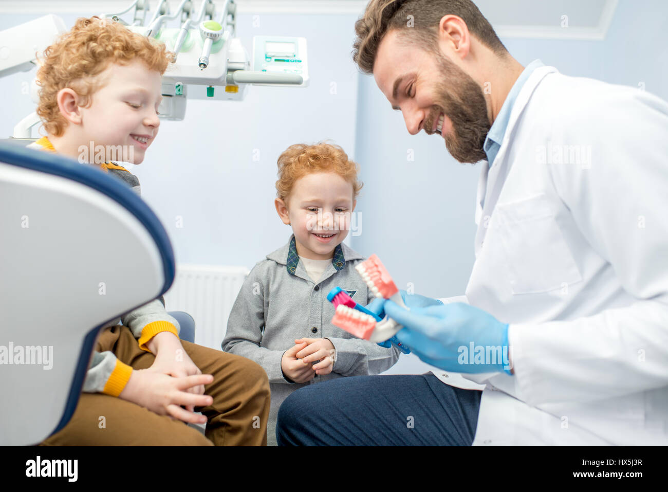 Bambini il dentista che mostra i ragazzi come spazzola denti sulla ganascia artificiale presso lo studio dentistico Foto Stock