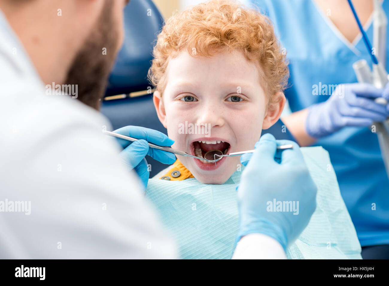 Bambini examinating dentista baby denti di un giovane ragazzo seduto sulla poltrona odontoiatrica presso l'ufficio Foto Stock