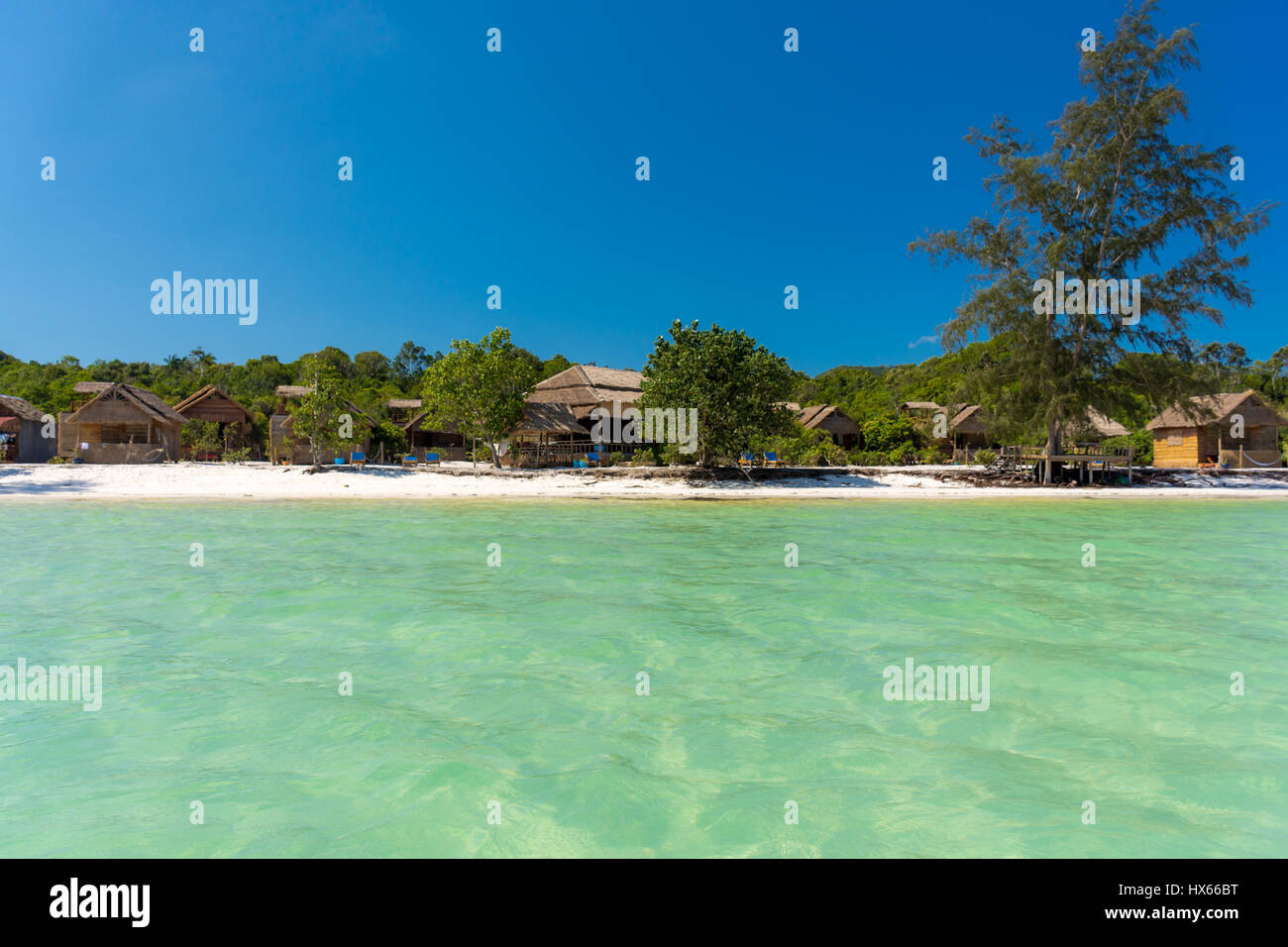 Bungalow vacation resort sulla spiaggia paradiso attraverso un chiaro mare vuota. Foto Stock