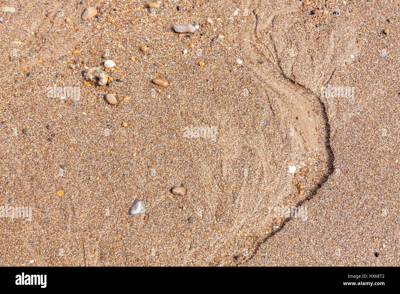 Il grintoso sabbia texture. Chiudere fino al di sopra di una spiaggia sabbiosa con piccole pietre e i segni lasciati dal flusso di acqua di mare, England, Regno Unito Foto Stock
