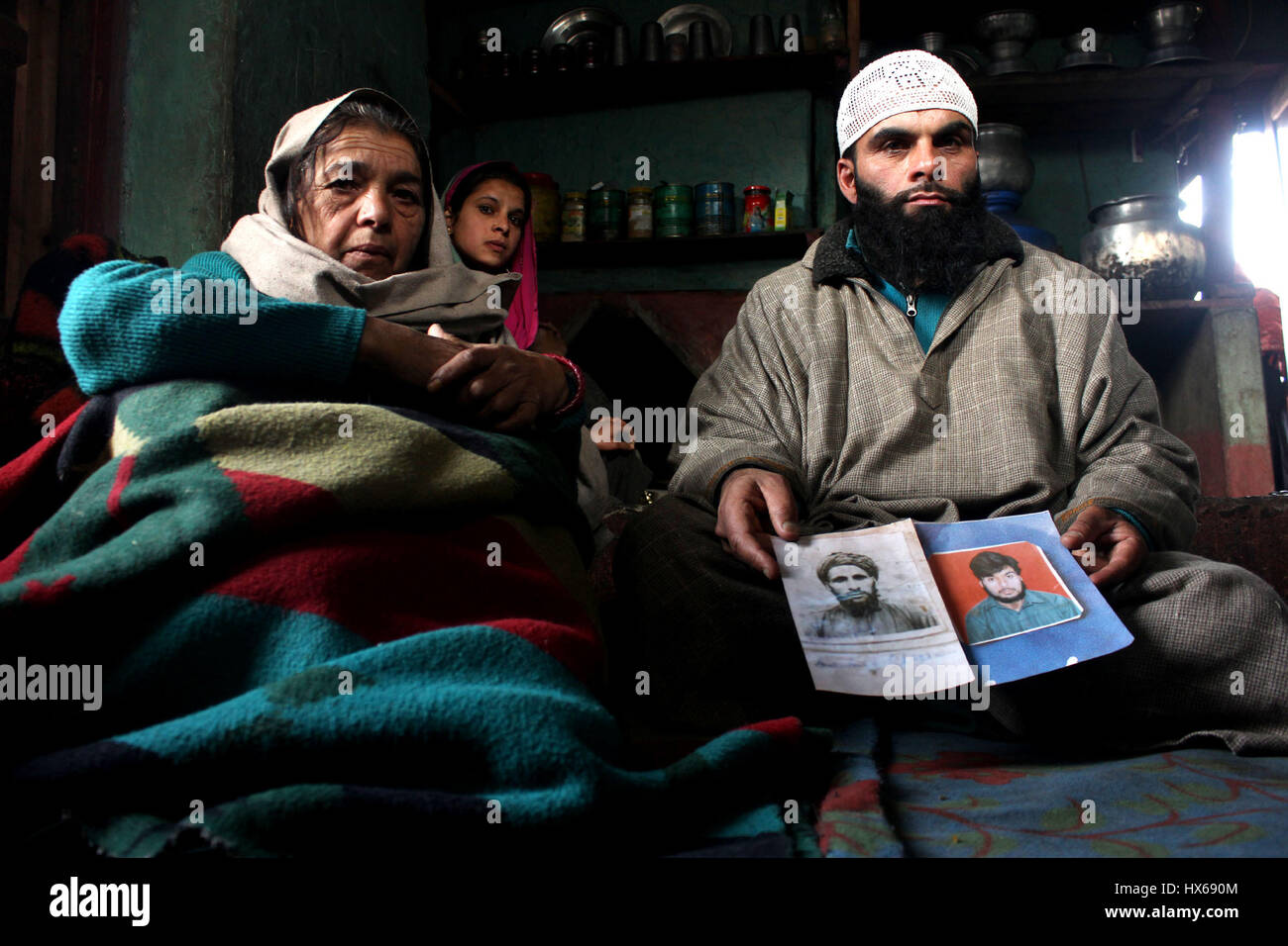 Anantnag, India. 25 Mar, 2017. Rashid Khan figlio e sua madre Zooni una delle vittime e un testimone chiave nel caso tenendo le foto di suo padre e suo fratello il 17 anniversario di uccisioni, la vittima le famiglie organizzando un ricordo si incontrano a Brari-Aangan villaggio di Shangus in questo Sud Kashmir distretto per ricordare cinque persone uccise nella fase incontro gestito dall esercito e il successivo abbattimento di otto manifestanti nel villaggio Brakpora dalla polizia e CRPF. Credito: Muneeb Ul Islam/Pacific Press/Alamy Live News Foto Stock