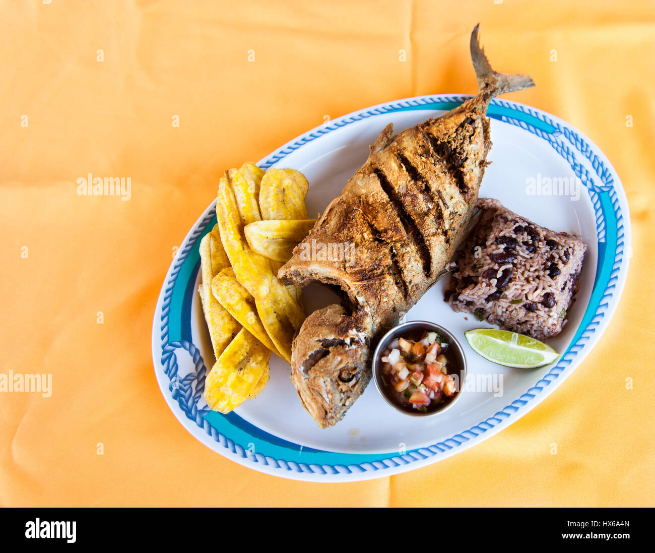 Pesce intero, riso con fagioli e piantaggine Chips Foto Stock