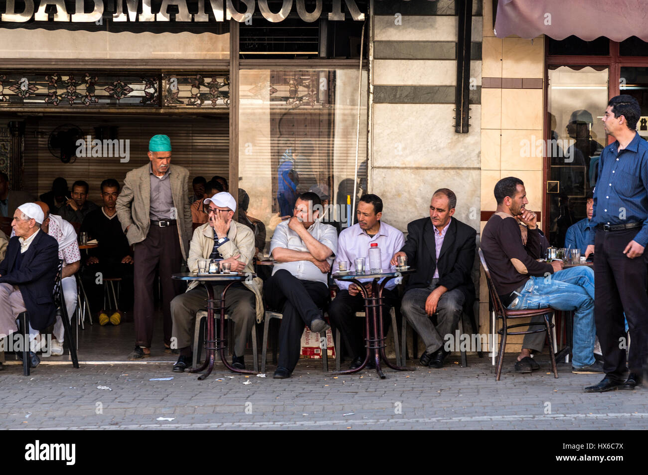 Meknes, Marocco. Gli uomini di relax presso un cafè sul marciapiede. Foto Stock