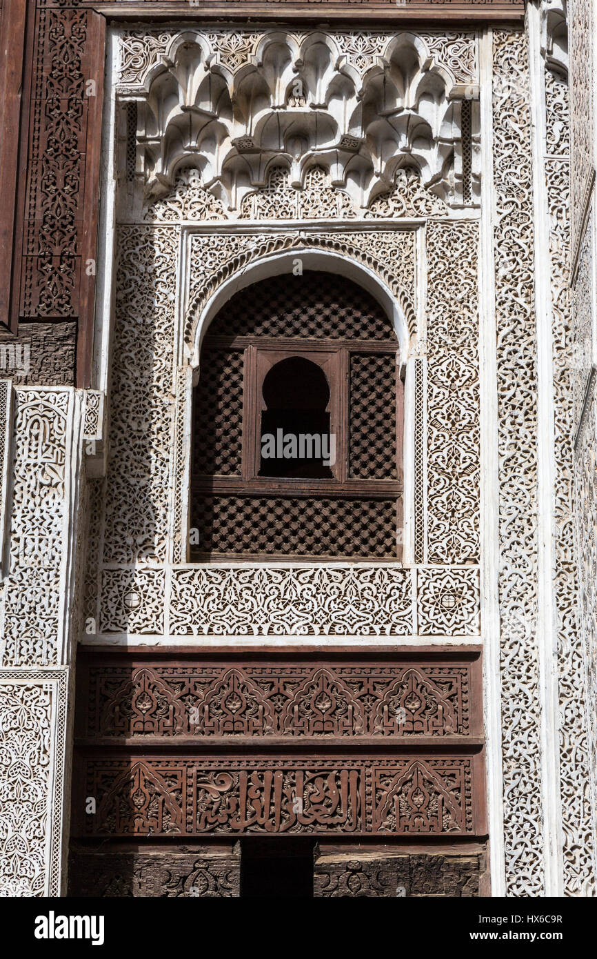 Meknes, Marocco. Medersa Bou Inania, 14th. Secolo. Decorazioni floreali in stucco e legno, e calligrafia, intorno a una finestra vista dal cortile interno. Foto Stock