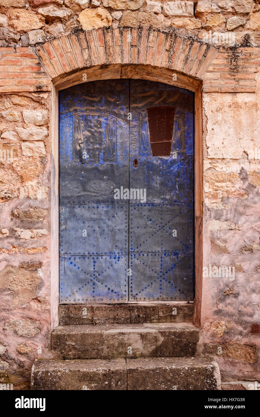 Fasi e una weathered blue porta in un vecchio muro, Albarracin, Spagna. Foto Stock