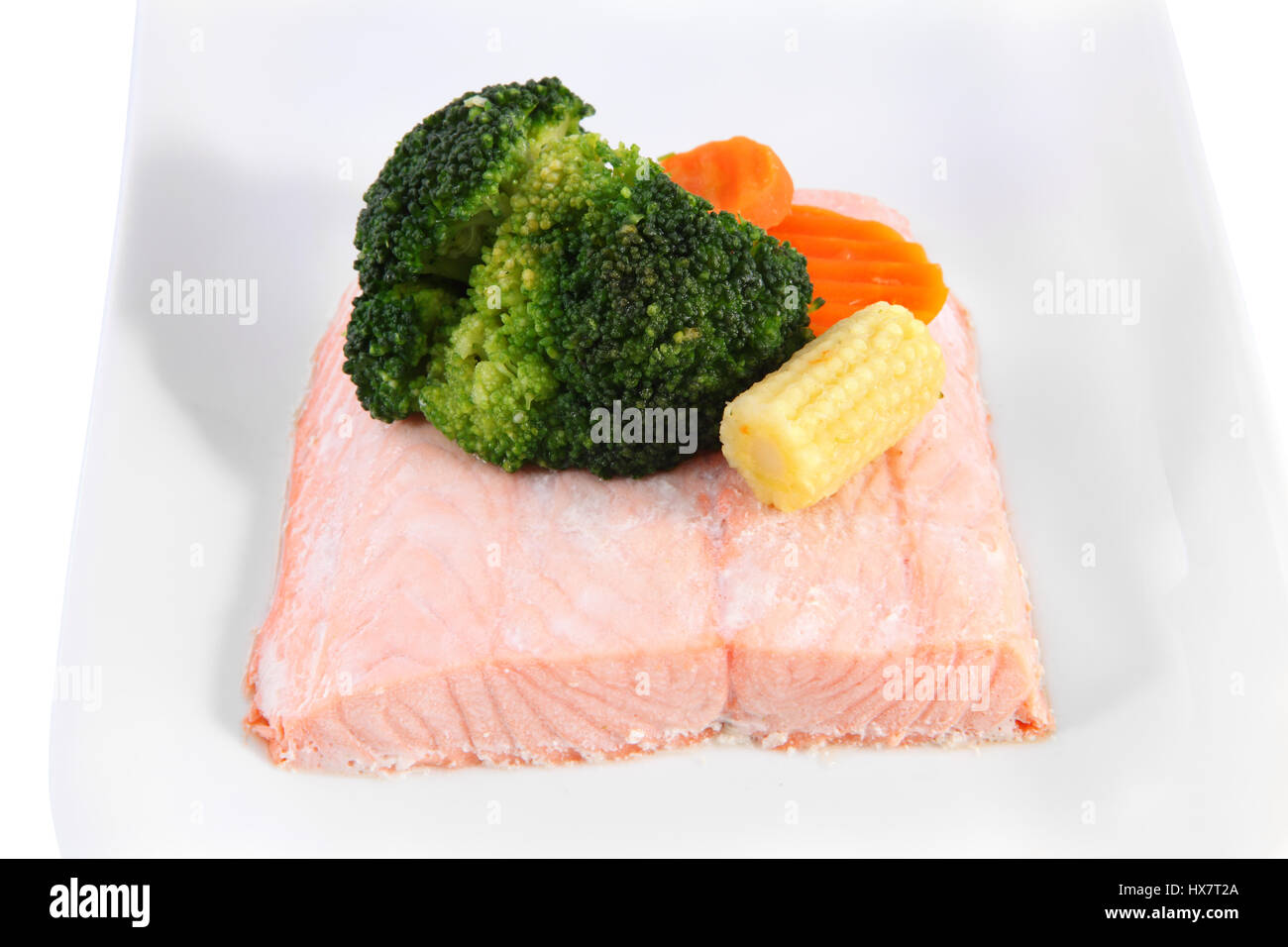 Primo piano di filetti di salmone cotto a vapore su una piastra con verdure marinate, giovani di tutoli di mais, e i broccoli. Foto Stock