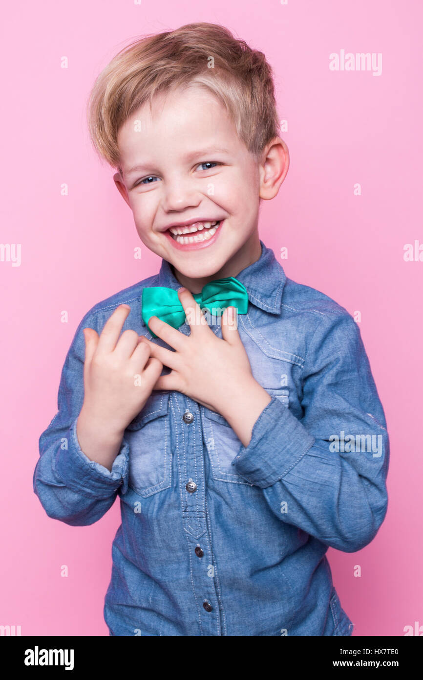 Giovani bel ragazzo con la maglietta blu e cravatta a farfalla. Moda. Modello. Ritratto in studio su sfondo rosa Foto Stock