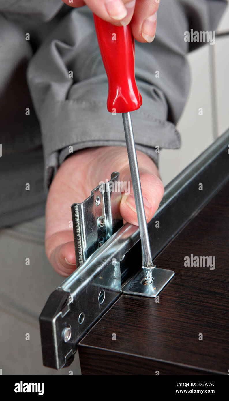 Assemblaggio di mobili, l'installazione di Mobile Runner cassetto cassetto, far  scorrere la staffa di fissaggio posteriore, avvitando la vite cacciavite  manuale Foto stock - Alamy
