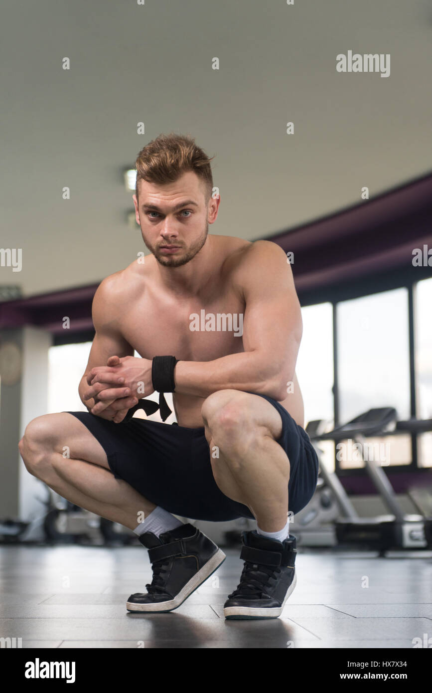 Buona ricerca e attraente Giovane con corpo muscoloso seduta sul banco di lavoro e relax nella palestra Foto Stock