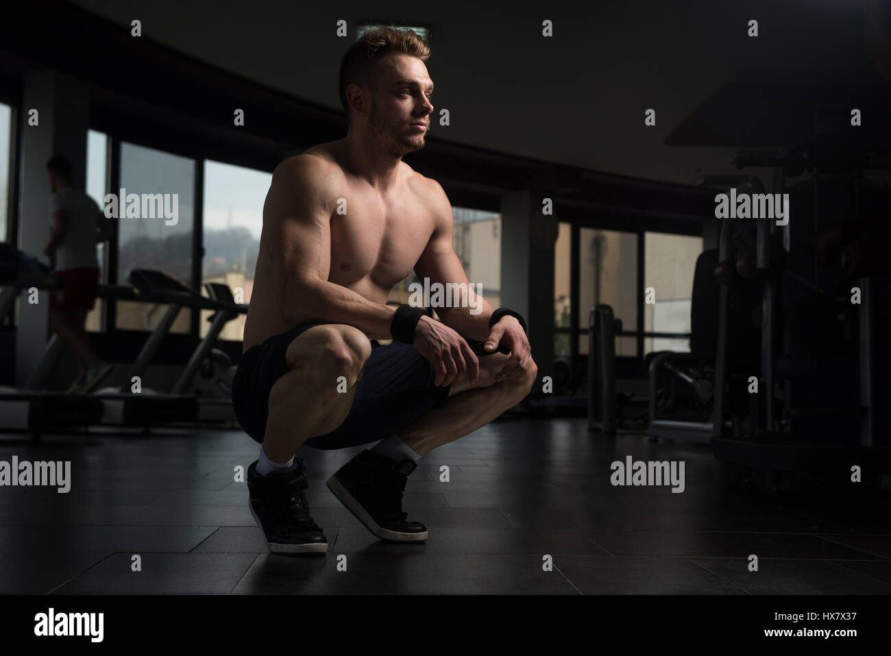 Buona ricerca e attraente Giovane con corpo muscoloso seduta sul banco di lavoro e relax nella palestra Foto Stock