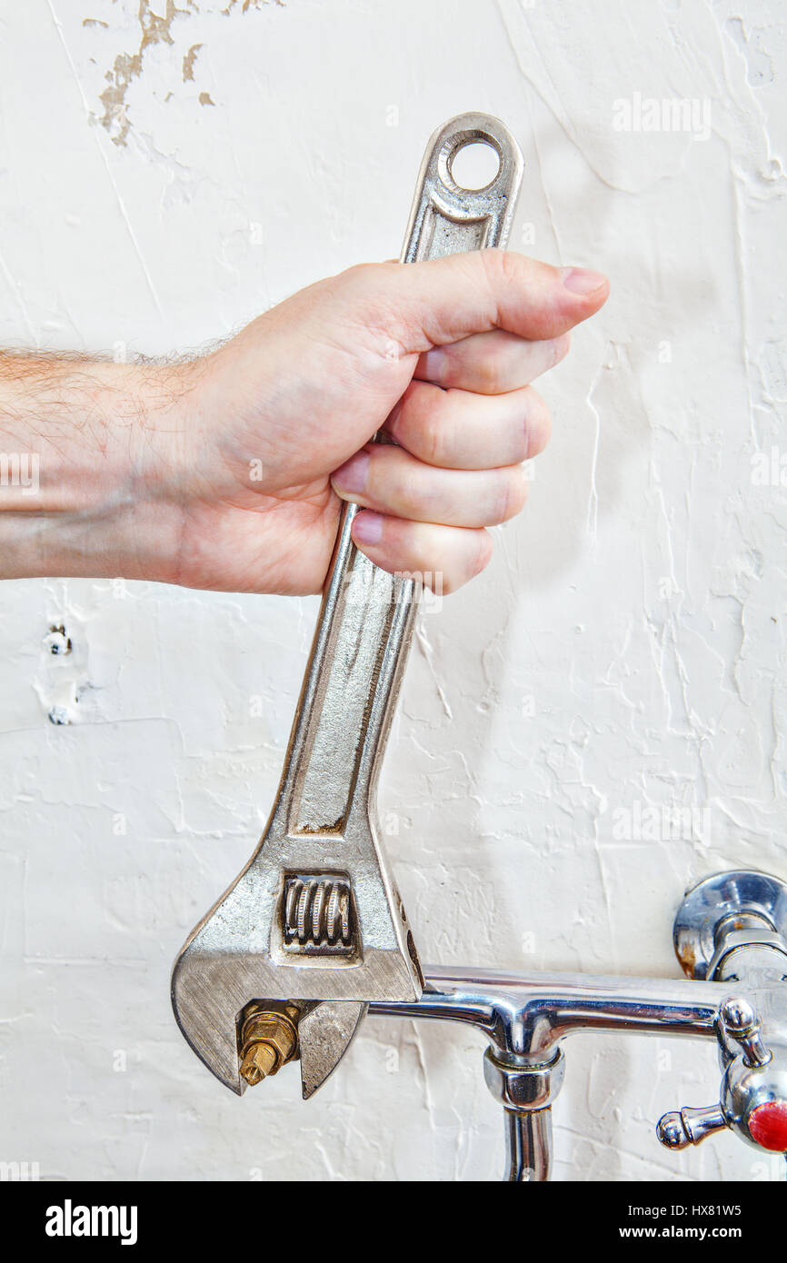 Due Impugnatura rubinetto di cucina riparazione, closeup idraulici mani serraggio valvola rubinetto utilizzando regolabile per idraulici chiavi. Foto Stock