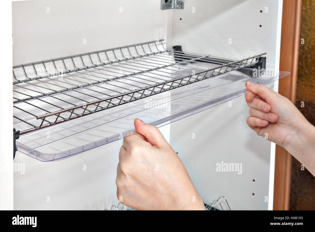 Installazione di ripiano sotto cappa da cucina con al suo interno la piastra metallica rack, close-up di una donna mani detiene il vassoio antigoccia. Foto Stock