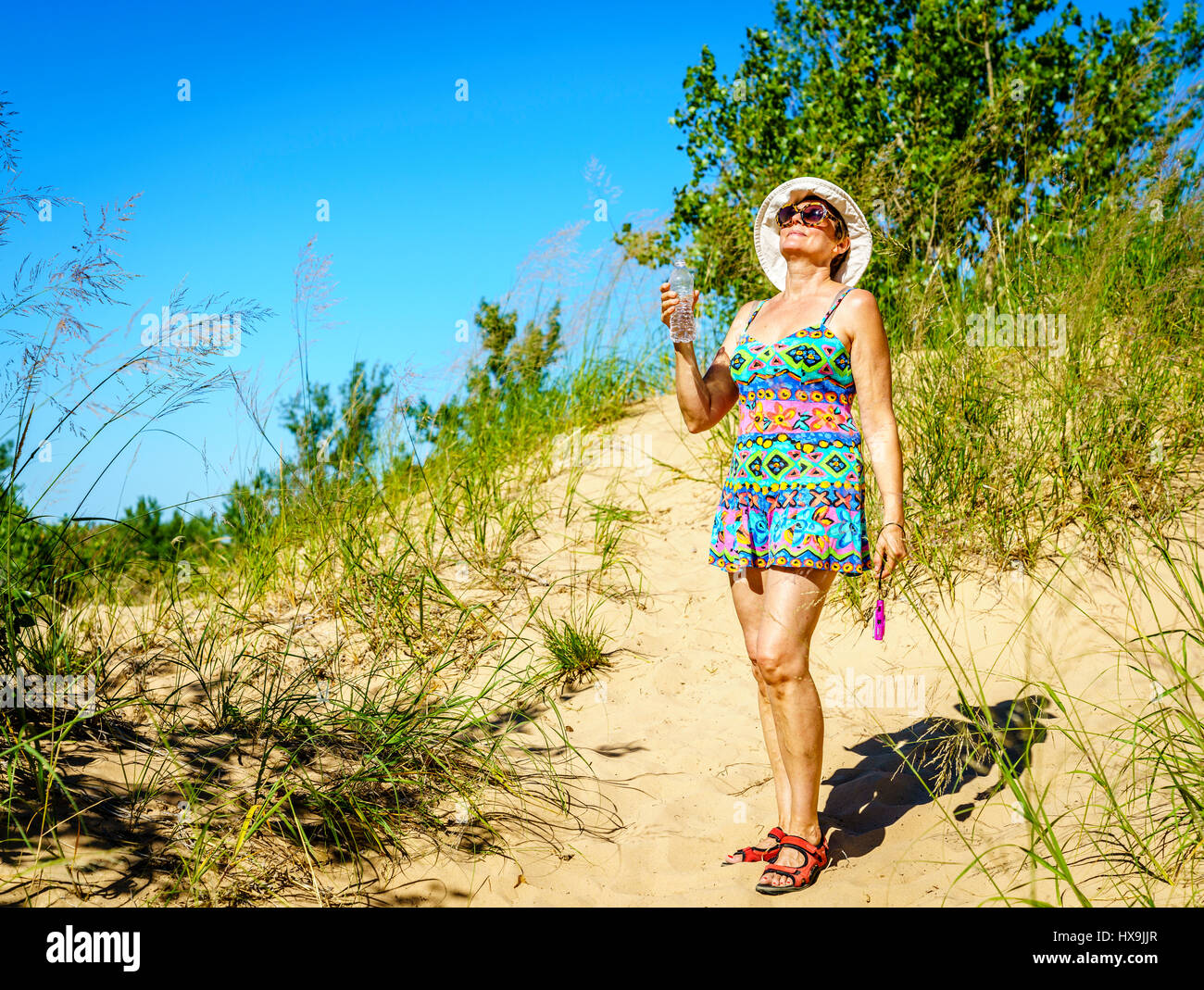 Donna felice con bottiglia di acqua su un sentiero attraverso la Sleeping Bear Dunes in Michigan settentrionale Foto Stock