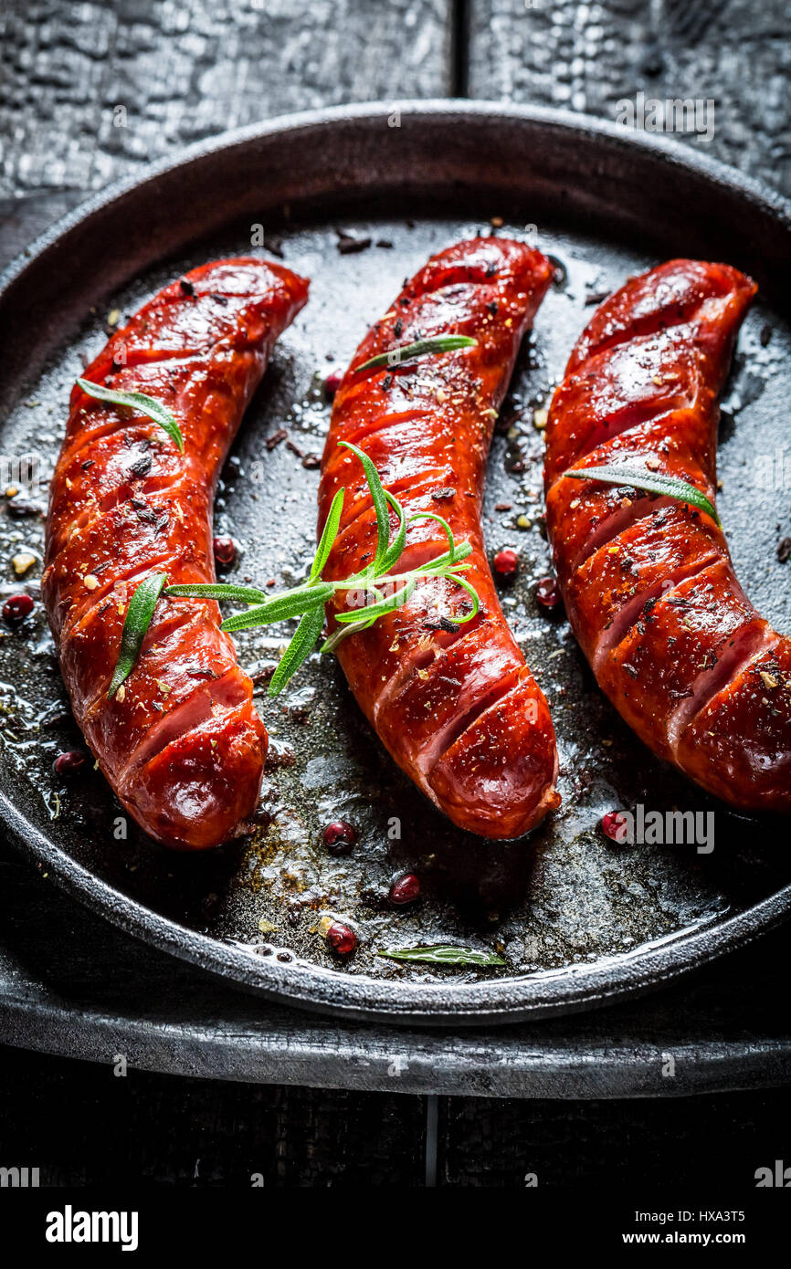 Salsicce arrosto con erbe fresche su nero bruciato tabella Foto Stock