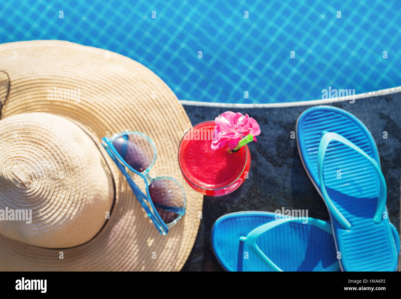 Acqua melone rosso succo fresco drink smoothie cocktail pantofole, cappello di paglia e occhiali da sole vicino alla piscina Foto Stock