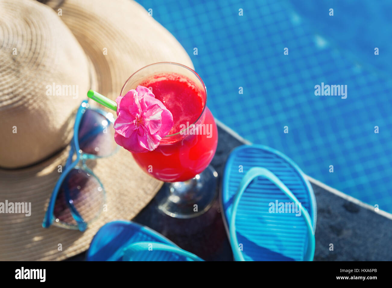 Anguria succo fresco drink frullato di vetro con fiori, occhiali da sole, pantofole e cappello di paglia sul bordo di una piscina - vacanza concetto tropicale Foto Stock