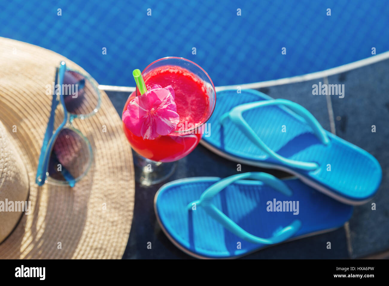 Anguria succo fresco drink frullato di vetro con fiori, occhiali da sole, pantofole e cappello di paglia sul bordo di una piscina - vacanza concetto tropicale Foto Stock