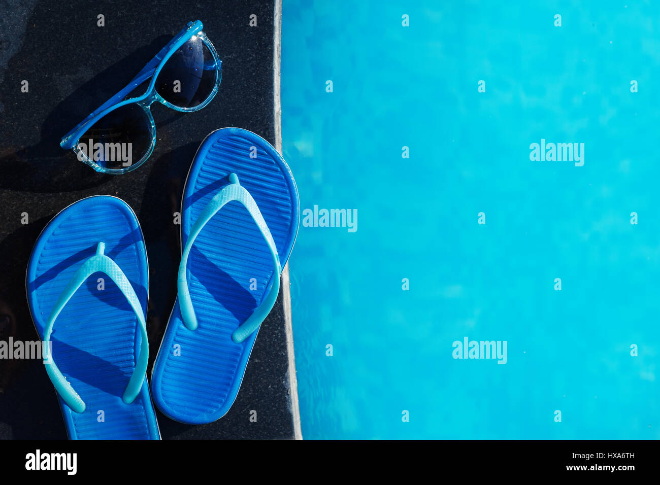 Pantofole blu e occhiali da sole vicino alla piscina - vacanza concept Foto Stock