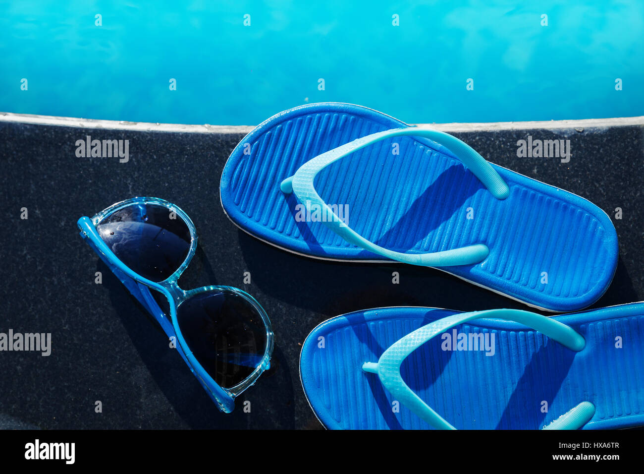 Pantofole blu e occhiali da sole vicino alla piscina - vacanza concept Foto Stock