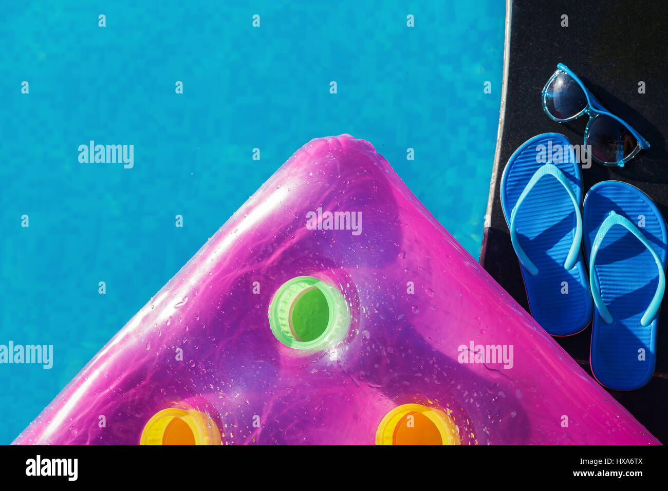 Rosa aria materasso, pantofole e sunglases sul bordo di una piscina - vacanza concetto tropicale Foto Stock