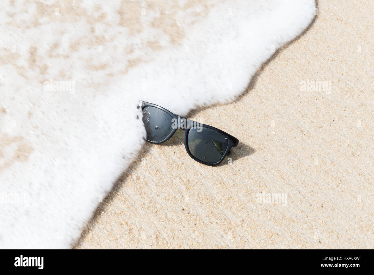 Occhiali da sole nero sulla spiaggia in acqua Foto Stock