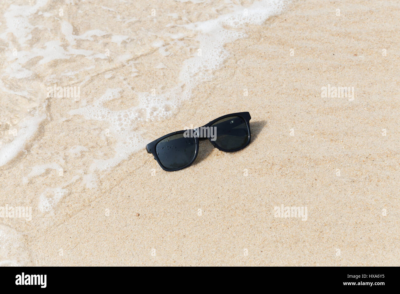 Occhiali da sole nero sulla spiaggia in acqua Foto Stock