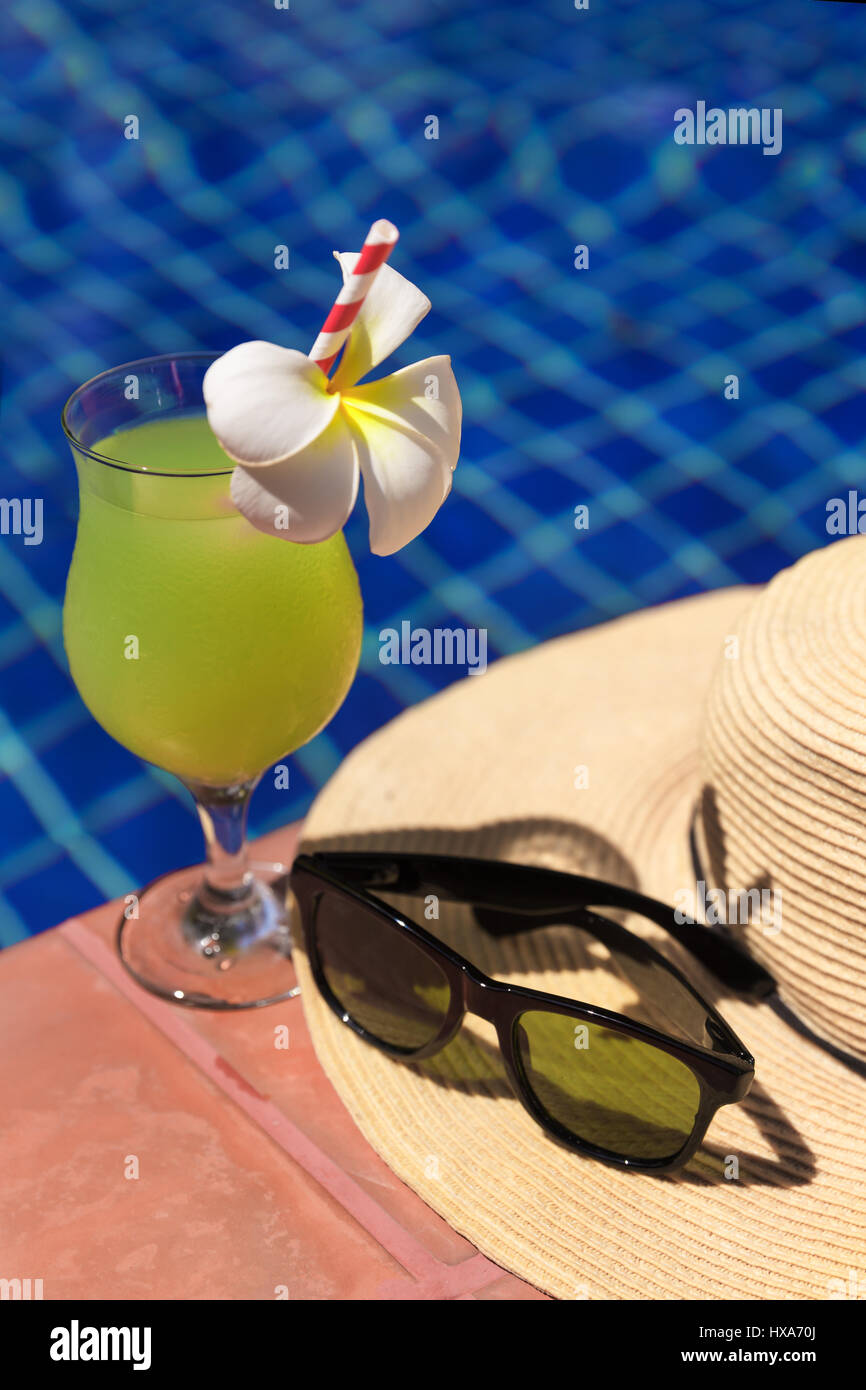Guaiava verde succo fresco drink smoothie cocktail, occhiali da sole e cappello di paglia vicino alla piscina - vacanza estiva concept Foto Stock