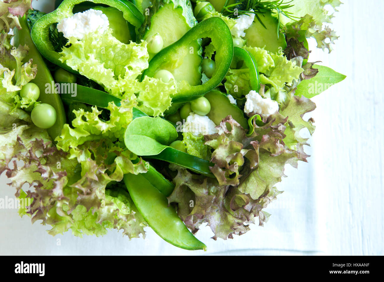 Organico verde mista insalata di verdure con formaggio feta e piselli primavera nella ciotola di legno close up - Dieta sana Organica Vegana cibo vegetariano insalata di pasto Foto Stock