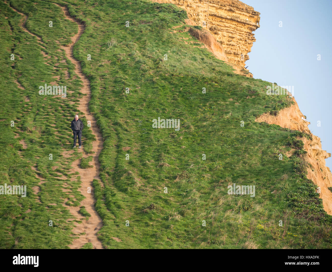 Un uomo godendo di alta sulla scogliera orientale come il sole come il cloud infine si cancella e un vago ma soleggiato pomeriggio segue. Con un meteo alto insieme a seguire e temperature più calde previsto per questo fine settimana. Burton Bradstock, Dorset, Regno Unito Foto Stock