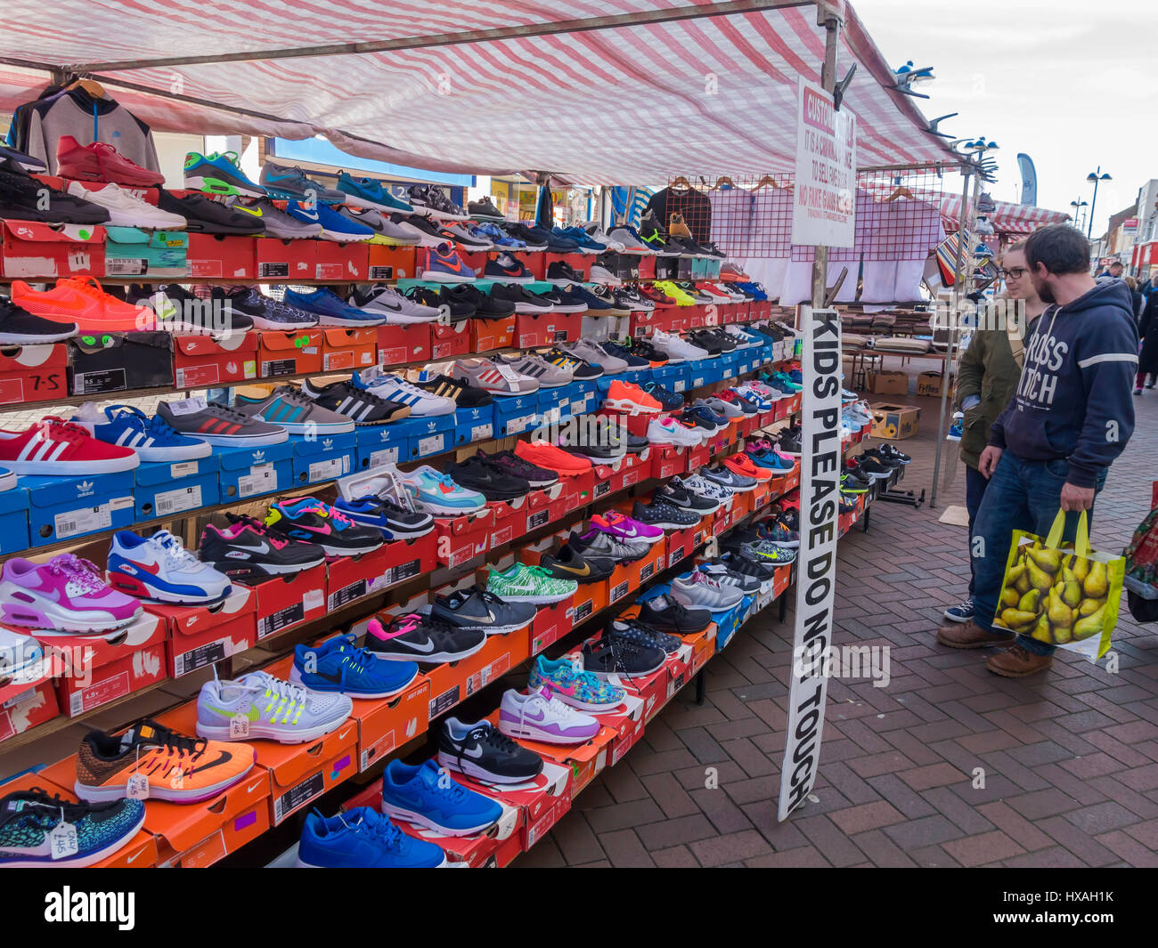 Shoppers guardando un display di marca Nike Trainer per la vendita su un mercato di strada in stallo. Foto Stock