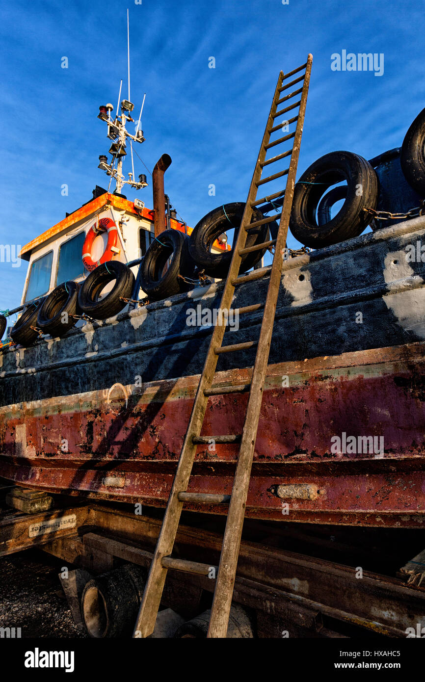 Una scala si appoggia contro una vecchia imbarcazione a Felixstowe Ferry, Suffolk, Inghilterra. Foto Stock
