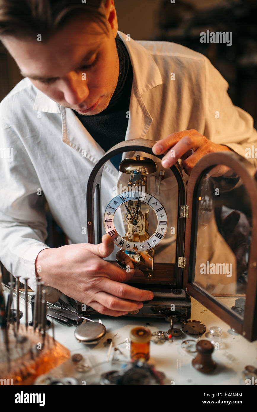 Orologiaio tenendo il vecchio orologio da tavolo. Antico orologio meccanico  riparazione in officina Foto stock - Alamy