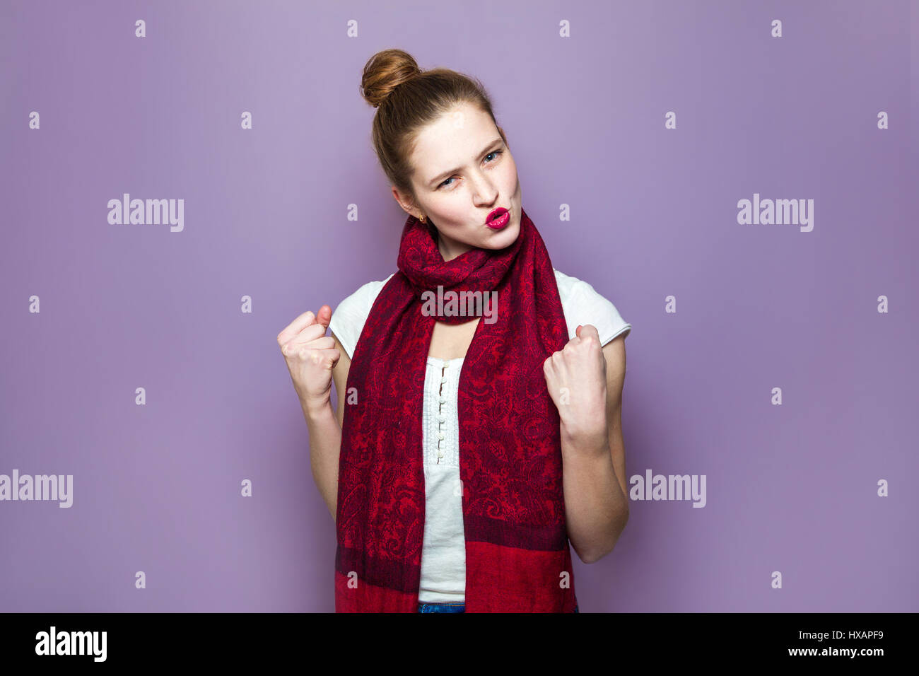 Il vincitore ha sorpreso la donna. Giovane bellezza emotiva con i capelli raccolti, lentiggini e sciarpa rossa cercando eccitati su sfondo viola, emozioni, espressioni Foto Stock