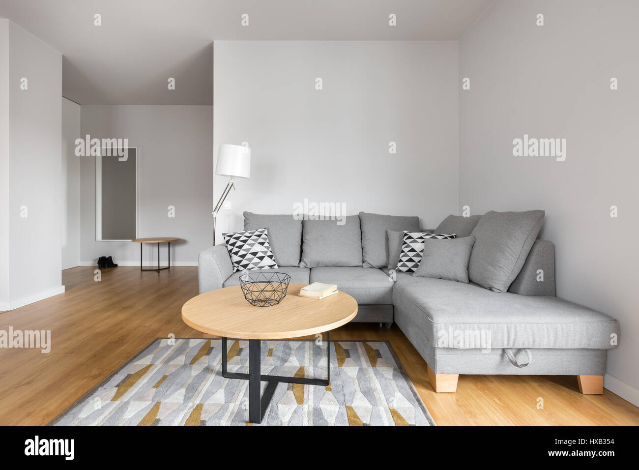 Soggiorno moderno con divano grigio con cuscini decorativi e tavolino  rotondo Foto stock - Alamy