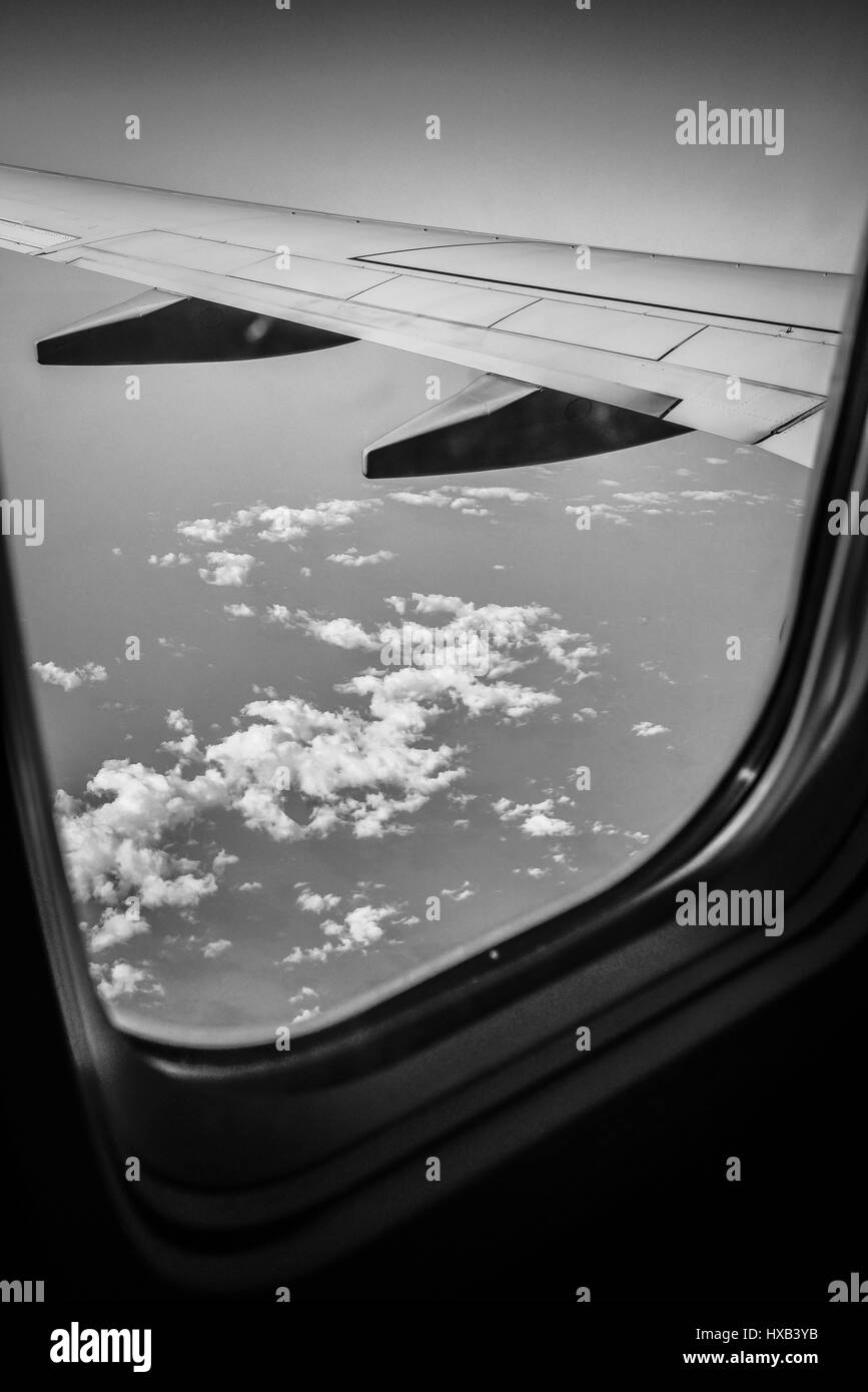 Un piano ala in primo piano con enormi nuvole bianche e blu cielo come visto dalla finestra del jet di linea commerciale Foto Stock