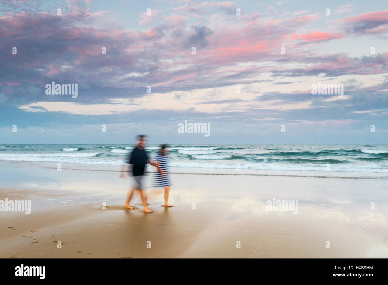 Giovane a piedi lungo le sabbie della spiaggia di Bargara al tramonto, Bundaberg, Queensland, Australia Foto Stock