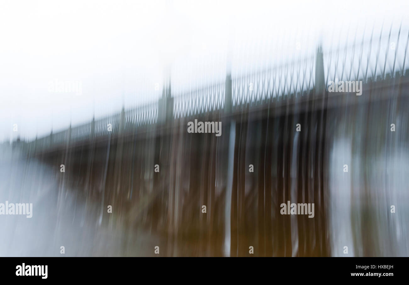 Immagine sfocata di un lungo ponte antico con un ferro battuto recinzione nella nebbia, realizzata con una lunga esposizione. Il concetto di un lungo e duro cammino, difficoltà e depressione. alterato stato di coscienza. Foto Stock