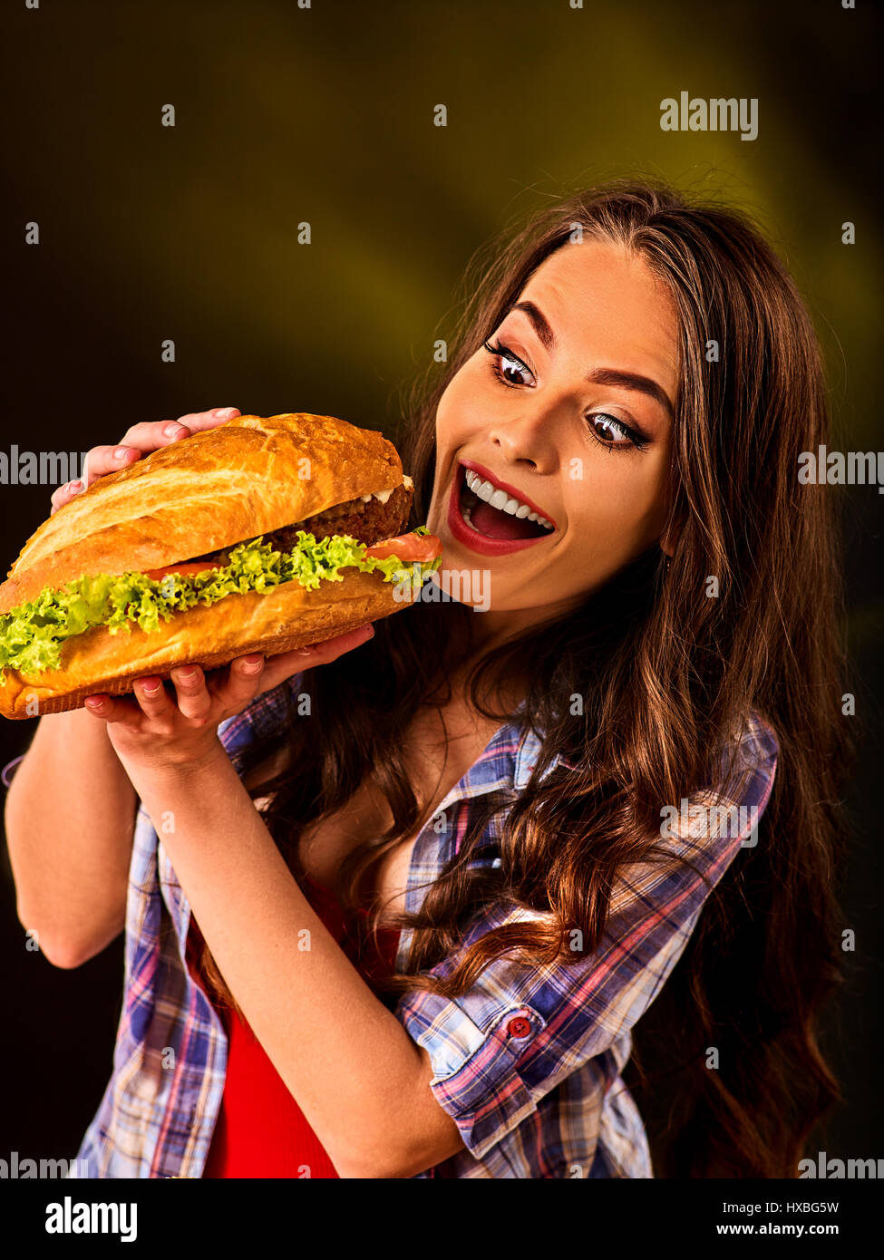 Donna di mangiare hamburger. Ragazza morso del grande burger Foto Stock